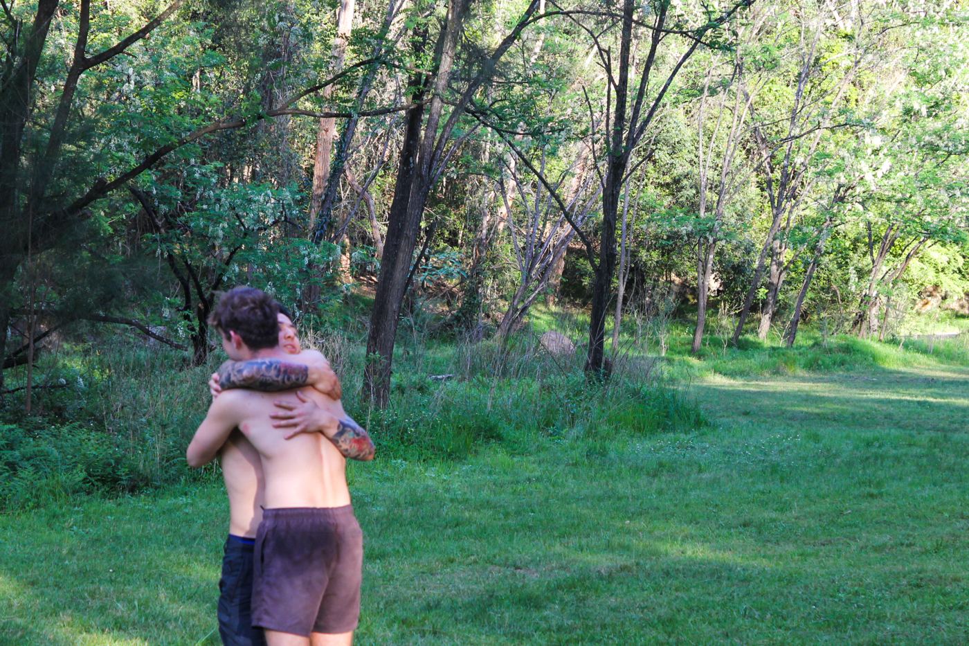 Two men embracing on a grassy clearing