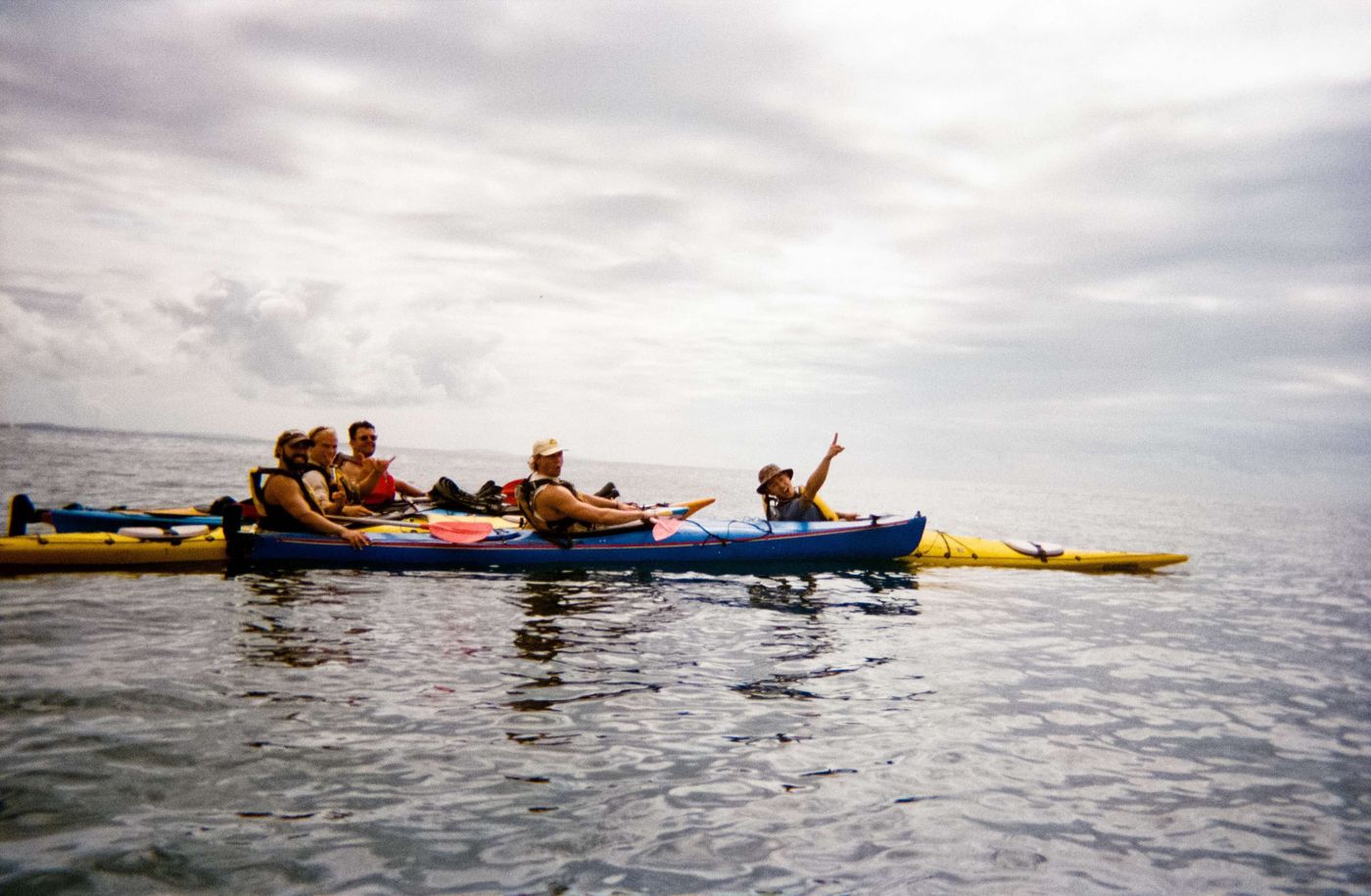 A raft of sea kayaks on flat water