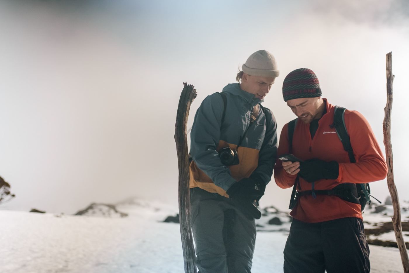 Two men checking a phone in the snow