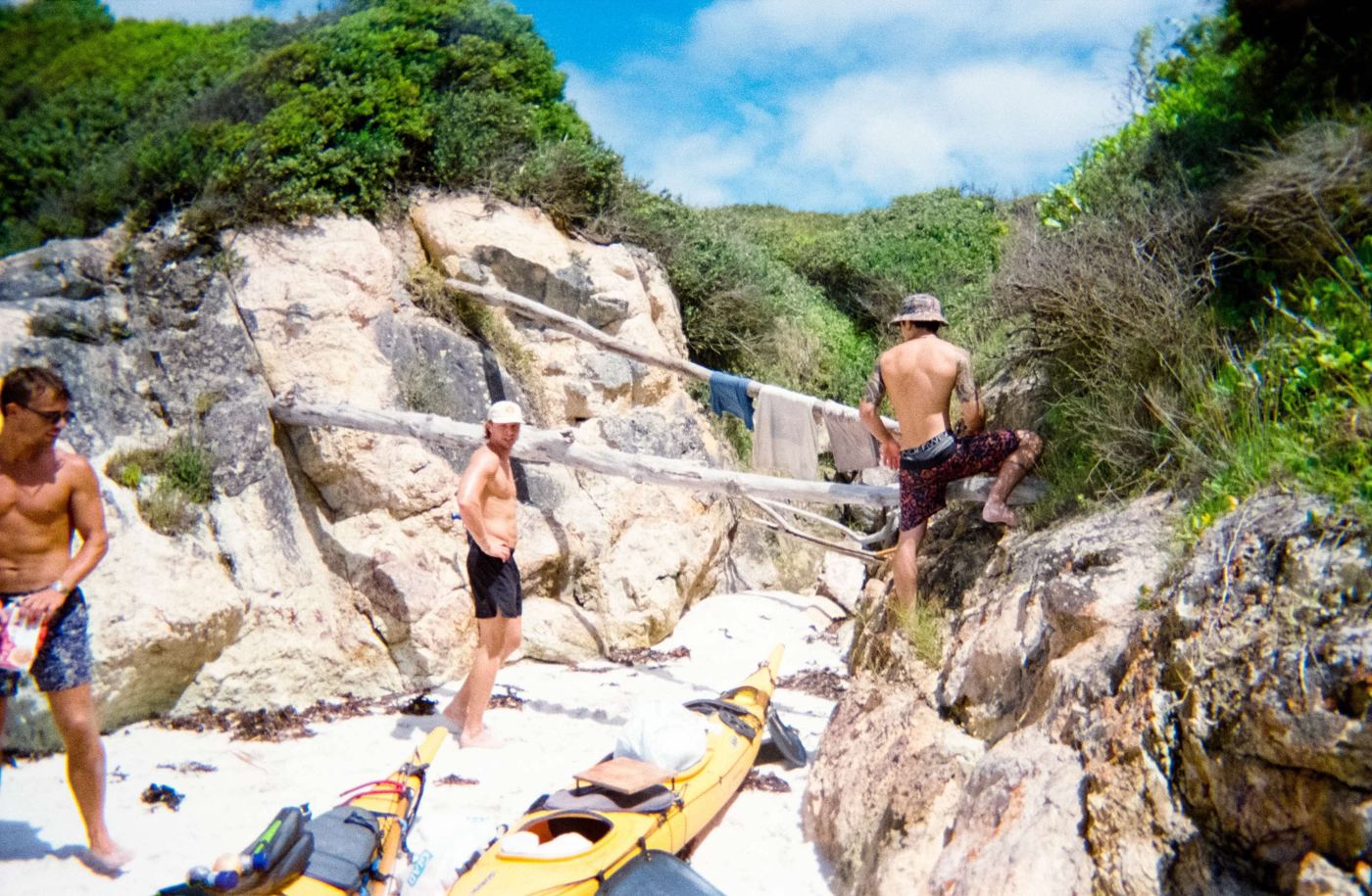 Men among the rocks with kayaks pulled up on the sand