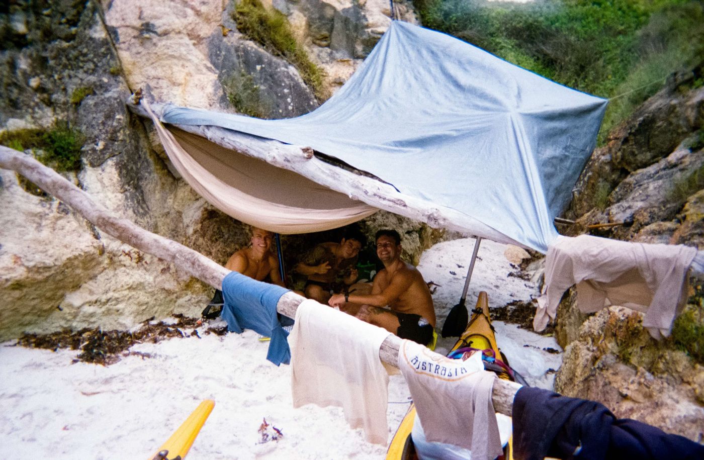 A tarp strung between rocks over a sandy camp